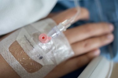 Kadın elinde enjeksiyonla hastanede yatarken elinde serum tutuyordu.