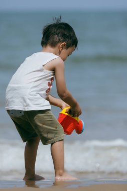 Kumsalda kumsalda oyuncaklarla oynayan Asyalı bir Çinli bebek. Çocuk oyunları. Kumsalda oyunlar