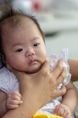 Yatakta yatarken gülümseyen Asyalı Çinli bebek kız. Mutlu yeni doğan çocuk yatakta dinleniyor.