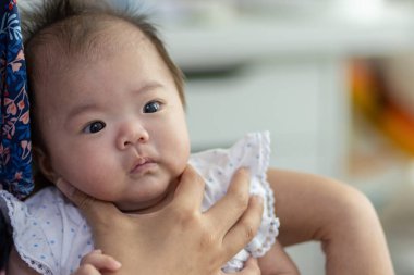 Yatakta yatarken gülümseyen Asyalı Çinli bebek kız. Mutlu yeni doğan çocuk yatakta dinleniyor.