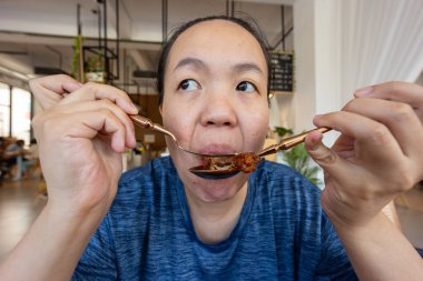 Asyalı Çinli bir kadının tavuk kanadı yerken portresi.