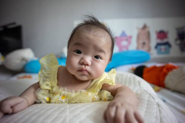 Yatakta yatarken gülümseyen Asyalı Çinli bebek kız. Mutlu yeni doğan çocuk yatakta dinleniyor.