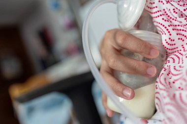 Asyalı Çinli anne yatak odasında bebeğine süt pompalamak için göğüs pompası kullanıyor. Colostrum süt, Geçiş sütü, Meme Pompalama süt konsepti.