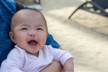 Gülümseyen Asyalı bebek mutlu görünüyor.