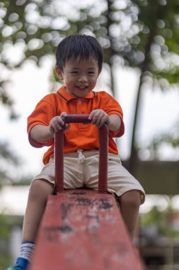 Mutlu Asyalı çocuk açık hava parkında oynamaktan hoşlanıyor.