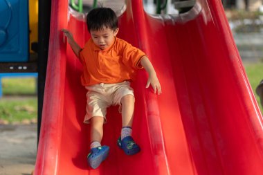 Mutlu Asyalı çocuk açık hava parkında oynamaktan hoşlanıyor.