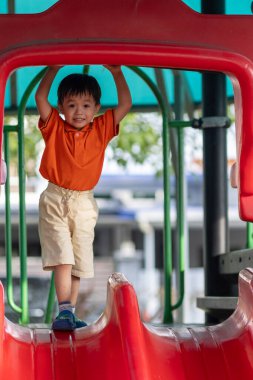 Mutlu Asyalı çocuk açık hava parkında oynamaktan hoşlanıyor.
