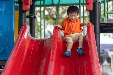 Mutlu Asyalı çocuk açık hava parkında oynamaktan hoşlanıyor.