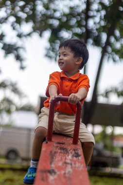 Mutlu Asyalı çocuk açık hava parkında oynamaktan hoşlanıyor.