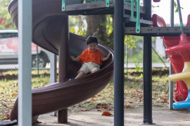 Mutlu Asyalı çocuk açık hava parkında oynamaktan hoşlanıyor.