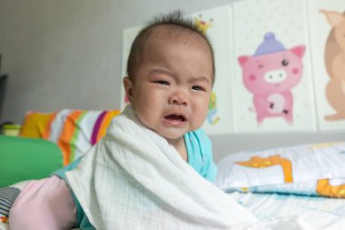 Yeni doğmuş bebek yatakta yatarken ağlıyor.