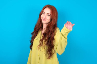 Mavi arka planda yeşil tişörtlü güzel, kızıl saçlı bir kadın. Eli ile gelmeye davet ediyor. Gelmene sevindim.