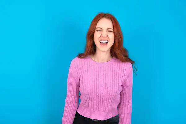 Stressful Red Haired Woman Wearing Pink Sweater Blue Background Screams — Stock Photo, Image