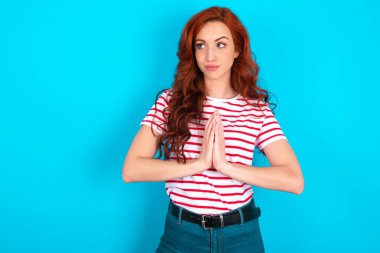 Çekici, genç, beyaz saçlı, mavi arka plan üzerinde çizgili tişört giyen, el ele tutuşup bir fikir oluşturan,.