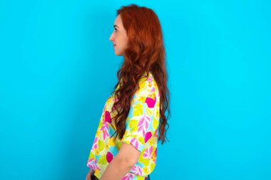 Mavi arka planda renkli gömlek giyen beyaz saçlı hoş bir kadının profil portresi boş dişli bir gülümsemeye benziyor.