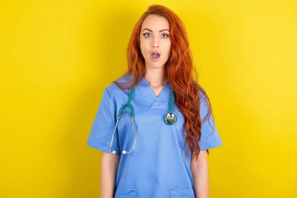 Σοκαρισμένη Νεαρή Κοκκινομάλλα Γιατρός Γυναίκα Πάνω Από Κίτρινο Φόντο Στούντιο — Φωτογραφία Αρχείου