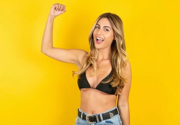 stock image Profile photo of young beautiful blonde woman wearing bikini over yellow studio background supporting soccer team World Cup 2022 raise fist shouting