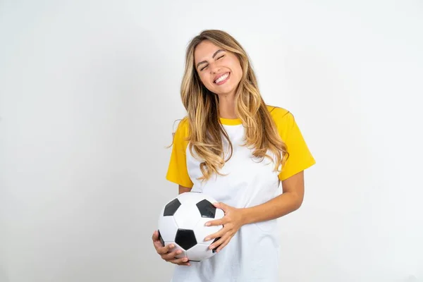 喜びの表情で白い背景にサッカーTシャツを身に着けている肯定的な若い美しい女性が目を閉じ 笑いショー白い完璧な歯 — ストック写真