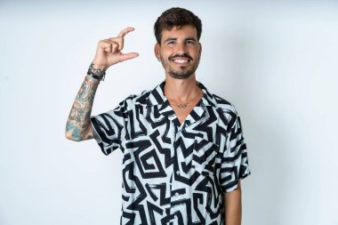 Baskılı tişört giyen, gülümseyen, kendine güvenen, el hareketi yapan, parmaklarıyla işaret yapan ve kameraya bakan genç beyaz bir adam. Ölçü kavramı