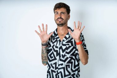 Baskılı tişört giyen genç beyaz adam korku ifadesinden korkuyor ve dehşete düşüyor. El hareketlerini durdur, şok içinde bağır. Panik konsepti.