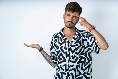 Baskılı tişört giyen genç beyaz bir adam avuç içinin açık olmasından rahatsız ve kafası karışmış bir şekilde fotokopi alanını gösteriyor ve alnını işaret ediyor. Bunu bir düşün..