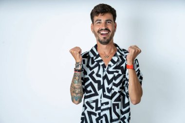 Baskılı tişört giyen genç beyaz adam kollarını kaldırıp, gözlerini açarak başarıyı kutluyor. Kazanan konsept.