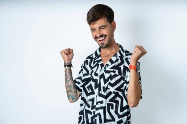 Yazlık tişörtlü bir adam izole edilmiş beyaz arka planda duruyor. Gülümsüyor, elleri göğsünde ve parmakları havada küfrediyor, sadakat yemini ediyor..