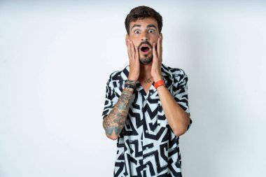 İzole edilmiş beyaz arka plan üzerinde duran dövmeli korkmuş adam dükkandaki, insani ve insani duygular kavramındaki fiyatlarla şok oldu.