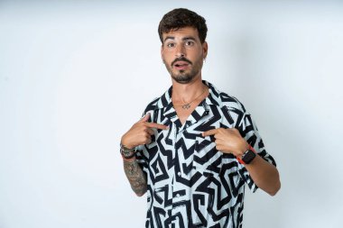 Yazılı tişört giyen utangaç genç beyaz bir adam şaşkın bir ifadeyle yarışmaya katıldığı için şoka uğruyor, bir konuda tereddüt ediyor.