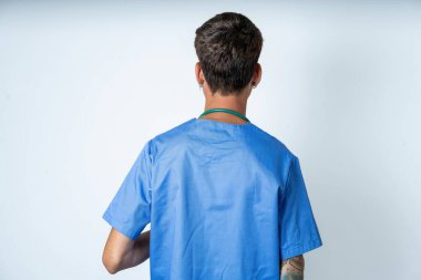 Beyaz arka planda cerrah üniforması giyen yakışıklı bir hemşire. Stüdyo Çekimi.