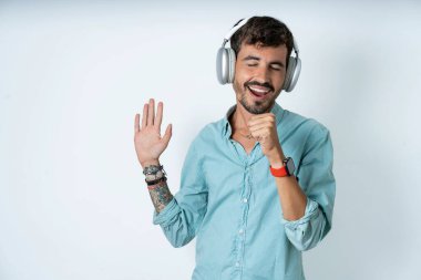 Beyaz arka planda turkuaz gömlek giyen yakışıklı genç adam en sevdiği şarkıyı söylüyor. Mikrofon kablosuz kulaklık takar gibi elini ağzından ayırmıyor, müzik dinliyor.