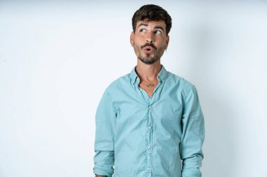 Beyaz arka planda turkuaz gömlek giyen, ağzı açık bir şekilde 