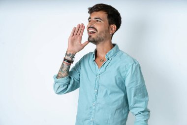 Beyaz arka planda turkuaz gömlek giyen yakışıklı genç adam boş görünüyor. El ele tutuşup çığlık atıyor ya da birini arıyor..