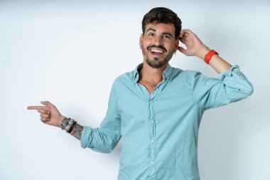 Beyaz arka planda turkuaz gömlek giyen yakışıklı genç adam el ele tutuşarak boş alanı işaret ediyor.