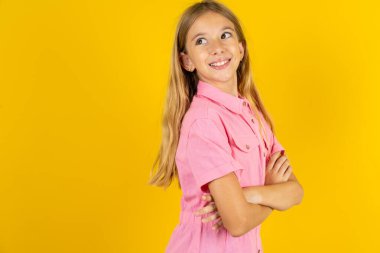 Sarı arka plan kolları üzerinde pembe ceketli kız boş reklam panosuna bak.