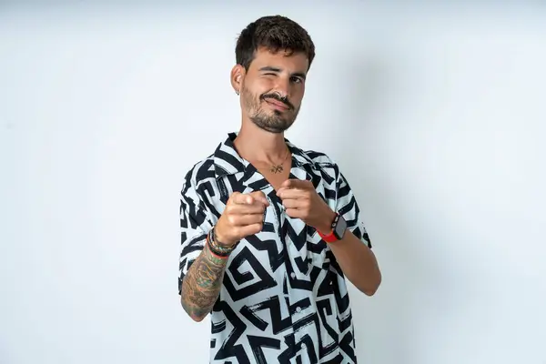 Fröhlicher Junger Kaukasischer Mann Mit Bedrucktem Hemd Zwinkert Und Zeigt — Stockfoto