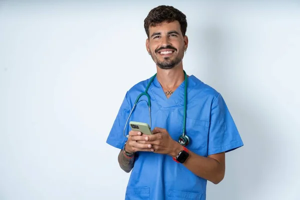 Kjekk Sykepleier Mann Iført Kirurg Uniform Hvit Bakgrunn Bruke Mobiltelefon – stockfoto