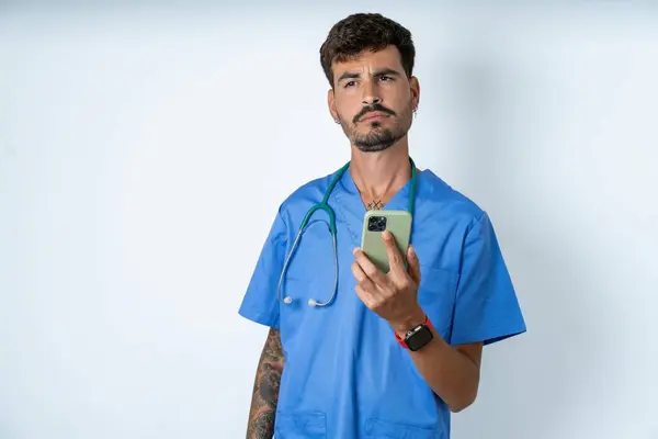 Handsome Nurse Man Wearing Surgeon Uniform White Background Holds Mobile — Stock Photo, Image