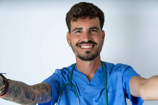 Photo of handsome nurse man wearing surgeon uniform over white background do selfie