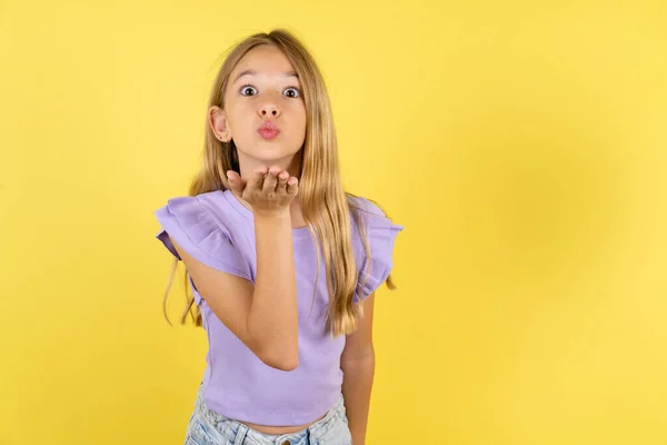 Blondynka Dziewczyna Fioletowym Shirt Żółtym Tle Patrząc Aparat Dmuchanie Pocałunek — Zdjęcie stockowe