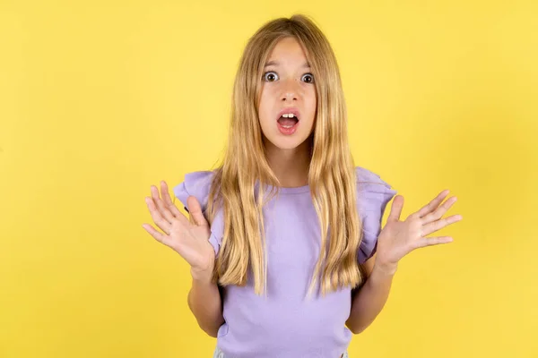 Sarı Arka Plan Jestleri Ile Mor Tişörtlü Şaşırmış Sarışın Kız — Stok fotoğraf