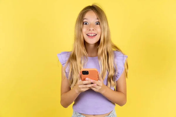 Opgewonden Meisje Draagt Violette Shirt Gele Achtergrond Holding Smartphone Kijken — Stockfoto