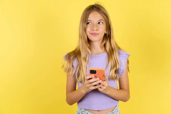 Blond Meisje Dragen Violet Shirt Gele Achtergrond Houdt Telefoon Handen — Stockfoto