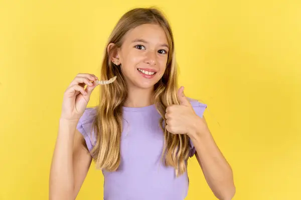Blonde Girl Wearing Violet Shirt Yellow Background Holding Invisible Braces — Stock Photo, Image