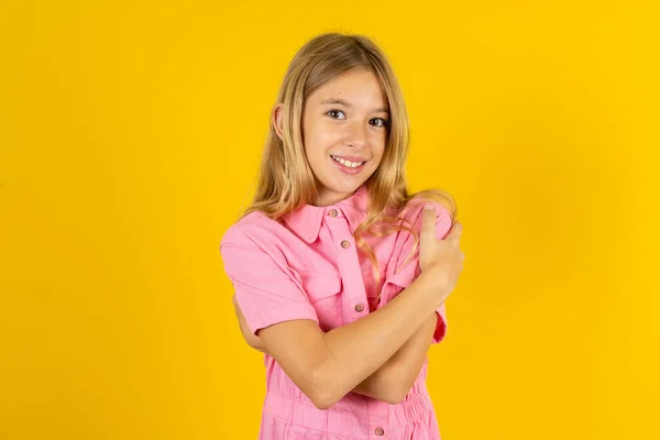 Charming Pleased Girl Wearing Pink Jacket Yellow Background Embraces Own — Stock Photo, Image