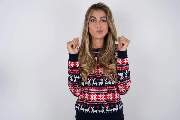 編まれたクリスマスのセーターを身に着けているイラストの美しいブロンドの女性は怒りで頬を吹き上げ クレンジングされた拳を上げて怒りと攻撃的な感情を表現します フューリアス モデル — ストック写真