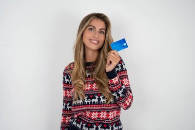 İyimser, sarışın, örgü örülmüş Noel süveteri giyen güzel bir kadının yakın çekim fotoğrafı.