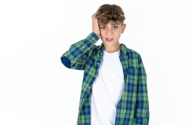 Beyaz arka planda ekose gömlekli, utangaç, yakışıklı bir genç çocuk, şok olmuş bir ifadeyle, büyük bir şaşkınlık içinde, bilmece gibi, kapalı alanda poz veriyor.