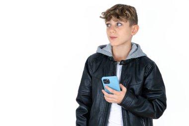 Deri ceketli yakışıklı çocuk beyaz stüdyo arka planında poz veriyor cep telefonu kullanıyor yüksek hızlı internet kullanıyor ve sosyal ağlarda internet iletişimi var. Modern teknoloji kavramı