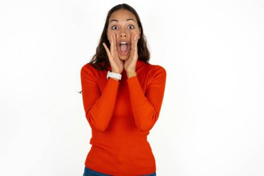 Beyaz arka plan üzerine kırmızı balıkçı yaka giyen genç İspanyol kadın heyecanla bağırıyor..